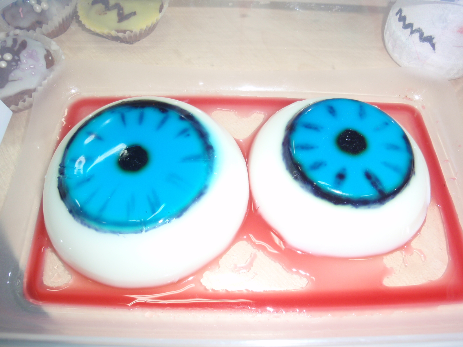 Na zdjęciu są 2 galaretki przedstawiające ludzkie oczy  w niebieskim kolorze. Wyglądaja jak żywe oczy.